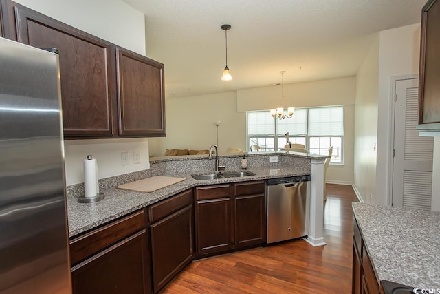 kitchen featuring sink, an inviting chandelier, dark hardwood / wood-style flooring, stainless steel appliances, and kitchen peninsula