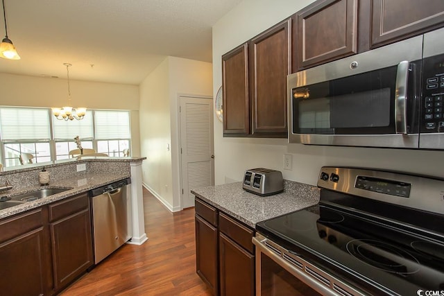 kitchen featuring appliances with stainless steel finishes, an inviting chandelier, dark hardwood / wood-style floors, dark brown cabinets, and hanging light fixtures