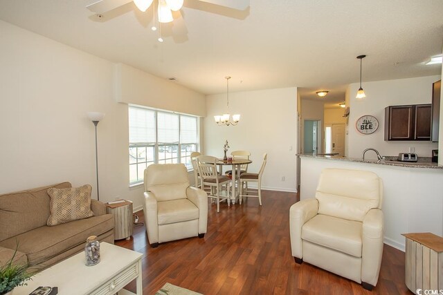 living room with ceiling fan with notable chandelier and dark wood-type flooring