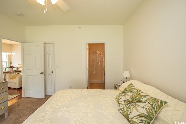 carpeted bedroom with ceiling fan with notable chandelier and ensuite bath