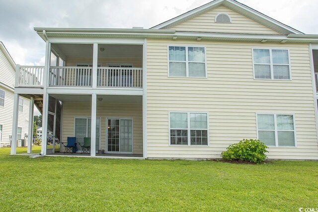 back of property with a balcony and a lawn