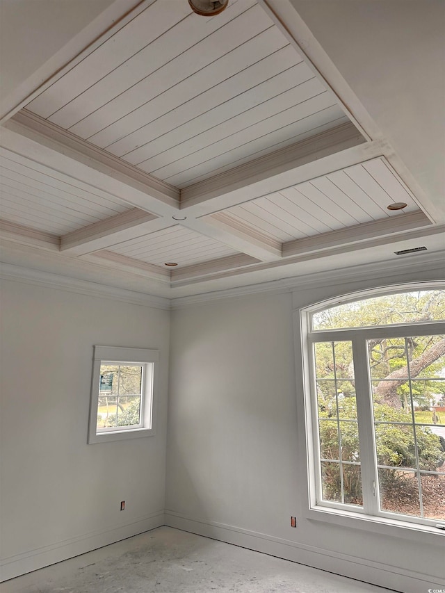 empty room with coffered ceiling, beam ceiling, crown molding, and concrete flooring