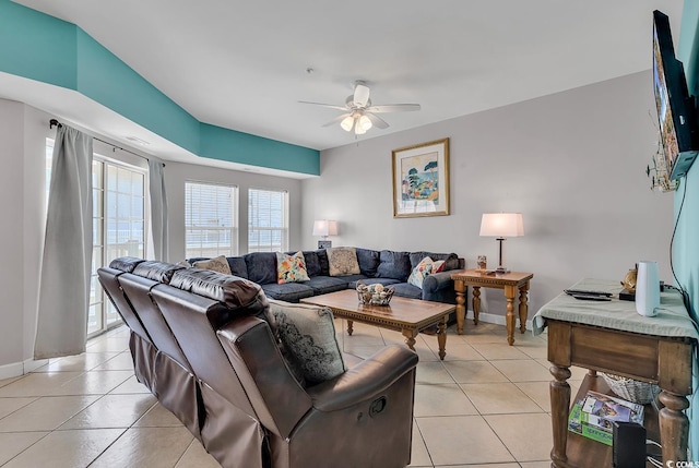 living area featuring light tile patterned floors, a ceiling fan, and baseboards