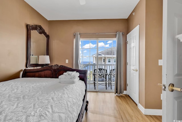 bedroom with access to outside, light wood finished floors, and baseboards