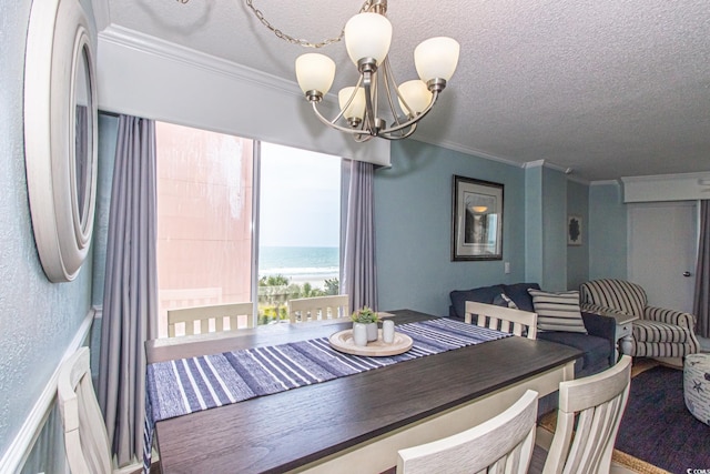 dining area with an inviting chandelier, a textured ceiling, ornamental molding, and a water view