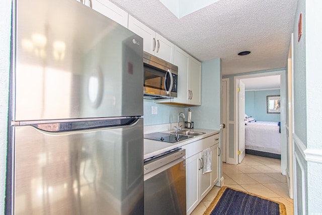 kitchen with appliances with stainless steel finishes, a textured ceiling, and white cabinets