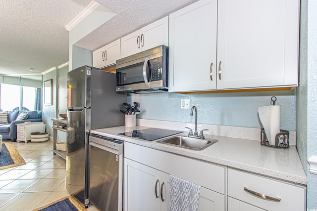 kitchen featuring a textured ceiling, light tile patterned flooring, sink, white cabinets, and appliances with stainless steel finishes