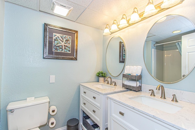 bathroom featuring toilet, a shower, vanity, and a paneled ceiling