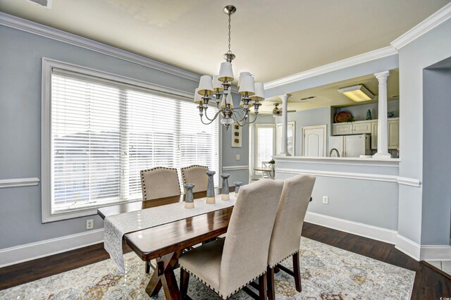 dining space featuring an inviting chandelier, dark hardwood / wood-style flooring, a wealth of natural light, and decorative columns