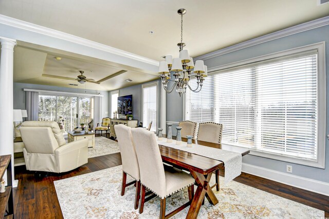 dining area with a tray ceiling, ceiling fan with notable chandelier, ornamental molding, decorative columns, and dark hardwood / wood-style floors