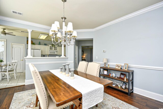 dining room featuring decorative columns, dark wood-type flooring, ceiling fan with notable chandelier, and ornamental molding