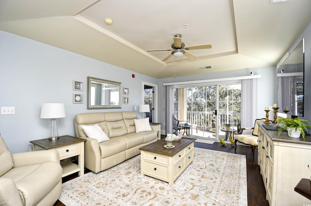 living room featuring light hardwood / wood-style flooring, ceiling fan, and a tray ceiling