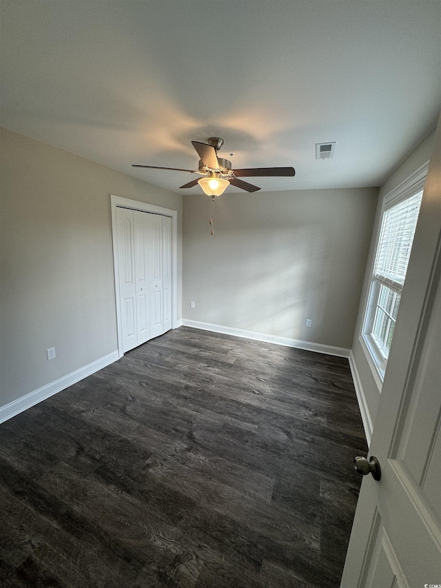 unfurnished bedroom with dark wood finished floors, baseboards, visible vents, and ceiling fan