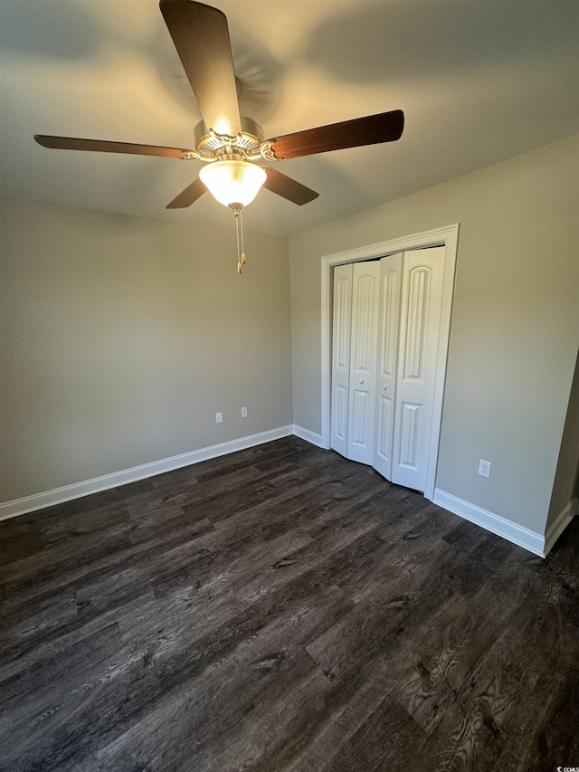 unfurnished bedroom featuring dark wood-type flooring, a ceiling fan, baseboards, and a closet