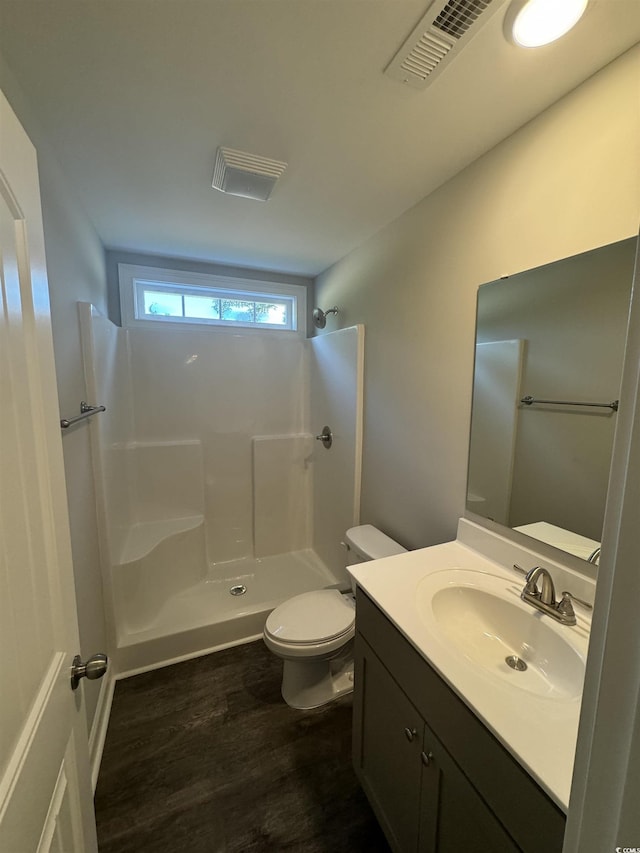 bathroom featuring vanity, wood finished floors, visible vents, a shower, and toilet