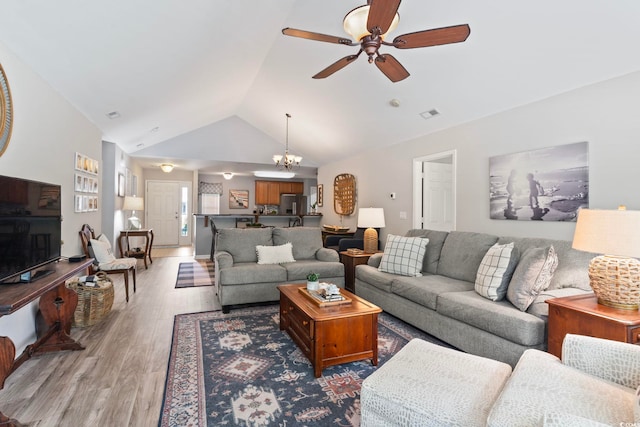 living room featuring lofted ceiling, ceiling fan with notable chandelier, and hardwood / wood-style flooring