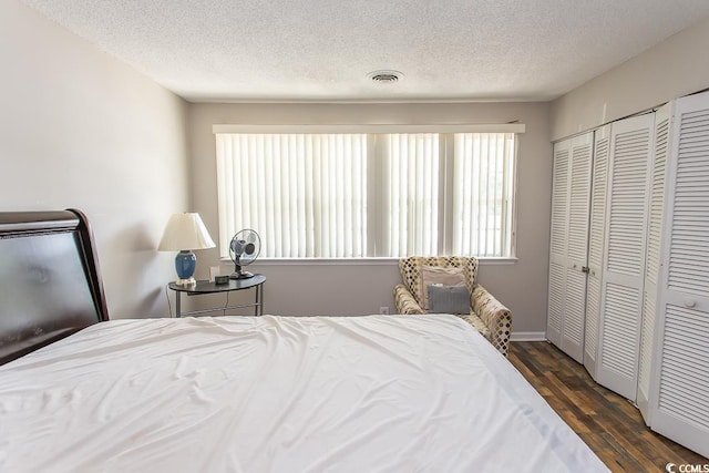 bedroom with dark hardwood / wood-style flooring, a textured ceiling, and a closet