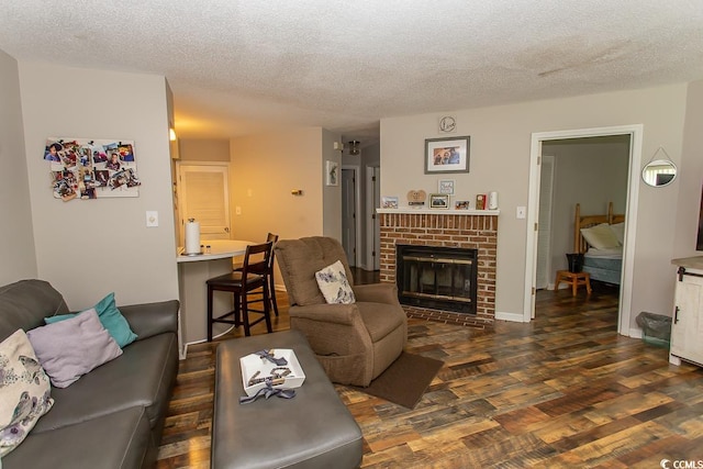 living room with a brick fireplace, a textured ceiling, and dark wood-type flooring