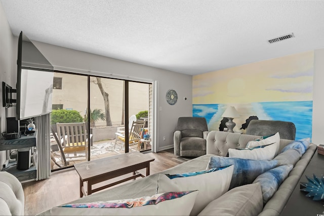 living area with visible vents, a water view, light wood-style flooring, and a textured ceiling