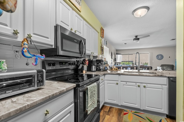 kitchen with black appliances, dark wood-type flooring, a sink, and white cabinetry