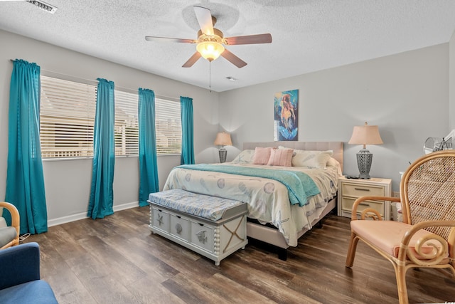 bedroom featuring dark wood-style flooring, visible vents, ceiling fan, a textured ceiling, and baseboards