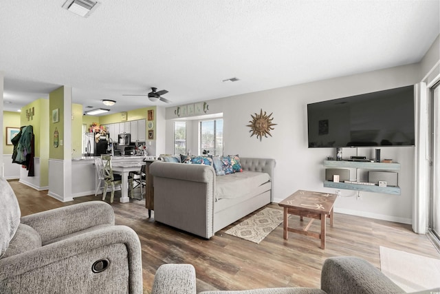 living area featuring a textured ceiling, wood finished floors, and visible vents