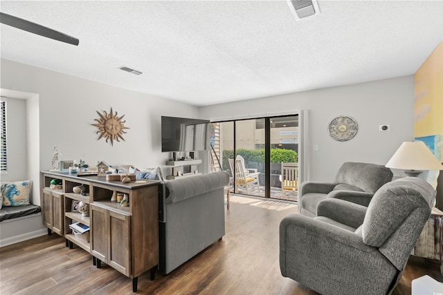 living room with visible vents, a textured ceiling, and wood finished floors