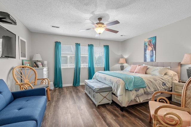 bedroom featuring dark wood-style floors, a textured ceiling, visible vents, and a ceiling fan