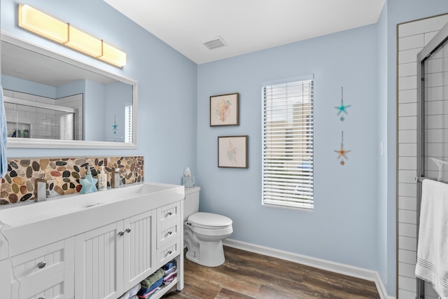 bathroom with baseboards, visible vents, toilet, wood finished floors, and vanity