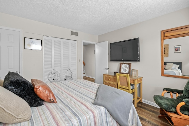 bedroom featuring baseboards, visible vents, dark wood-style flooring, a textured ceiling, and a closet