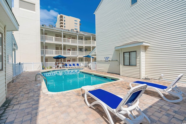 pool with a patio area and fence