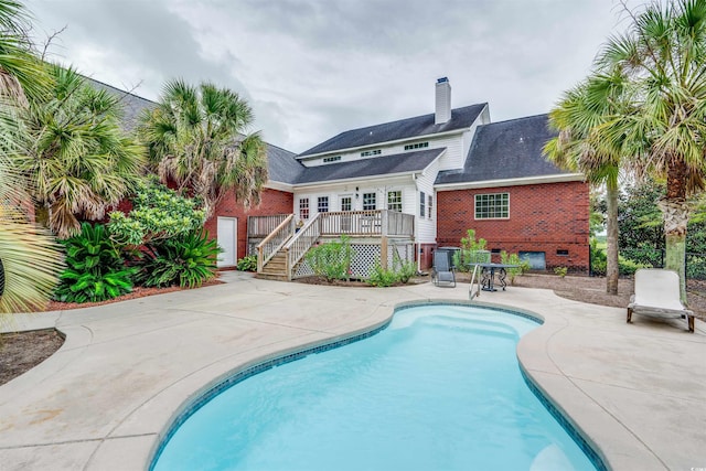 view of swimming pool featuring a wooden deck and a patio area