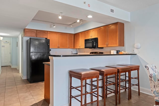 1321 S Ocean Blvd Unit 606, North Myrtle Beach, SC 29582 - kitchen featuring black appliances, light tile patterned floors, a peninsula, dark countertops, and a kitchen breakfast bar
