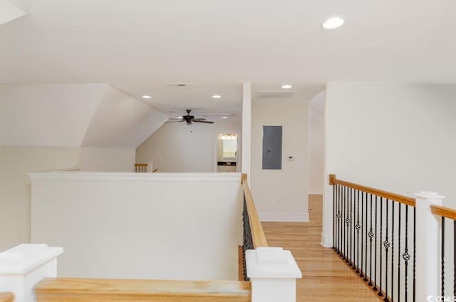 corridor featuring vaulted ceiling, electric panel, and light hardwood / wood-style floors