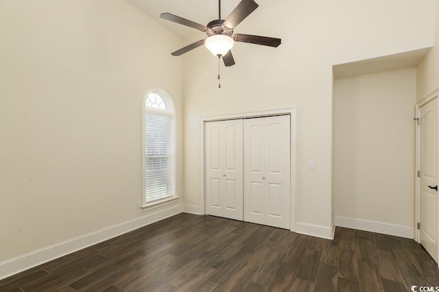 unfurnished bedroom featuring dark wood-type flooring, ceiling fan, high vaulted ceiling, and a closet