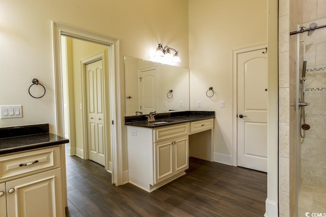 bathroom with hardwood / wood-style flooring, vanity, and tiled shower