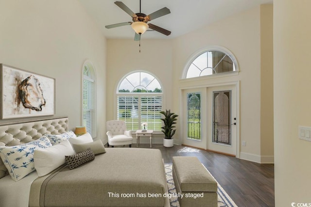 bedroom featuring dark hardwood / wood-style floors, access to exterior, multiple windows, and a high ceiling