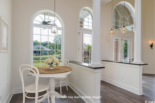 dining room featuring ornate columns, dark wood-type flooring, and a towering ceiling