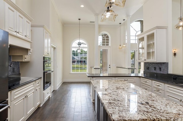 kitchen featuring backsplash, crown molding, hanging light fixtures, and dark stone countertops