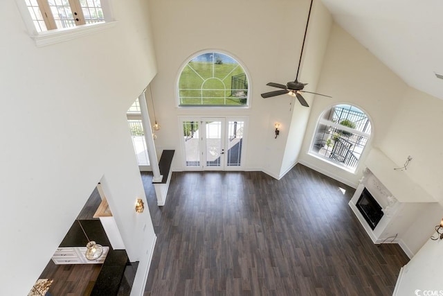 unfurnished living room featuring french doors, a healthy amount of sunlight, dark hardwood / wood-style floors, and a towering ceiling