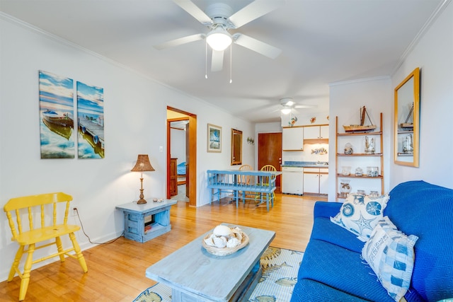 living area featuring ornamental molding, a ceiling fan, and light wood finished floors