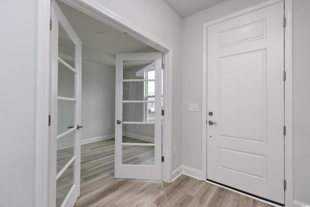 foyer entrance with french doors and light hardwood / wood-style floors