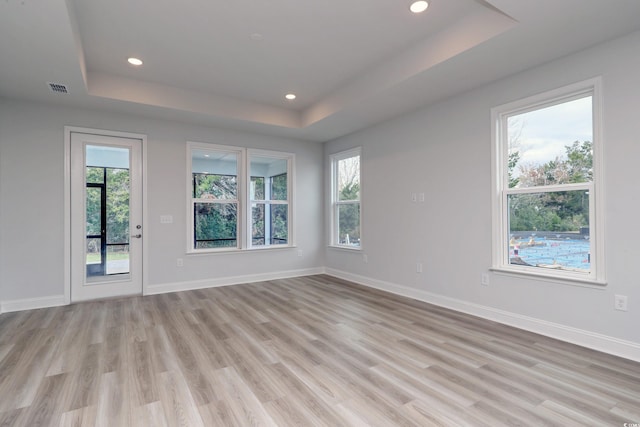 unfurnished room with a tray ceiling and light hardwood / wood-style floors