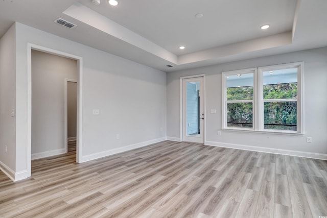 unfurnished room featuring light hardwood / wood-style floors and a raised ceiling