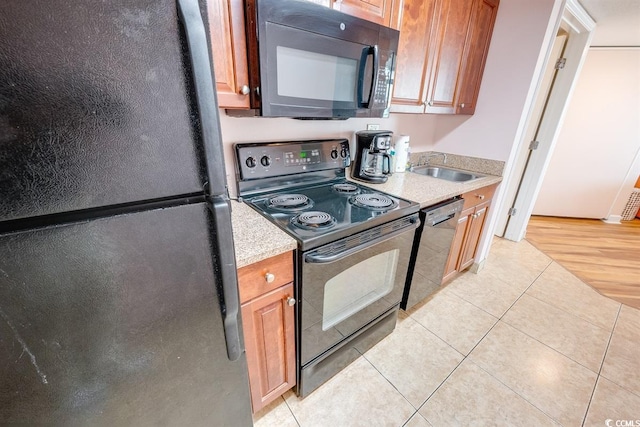 kitchen with sink, light tile patterned floors, and black appliances