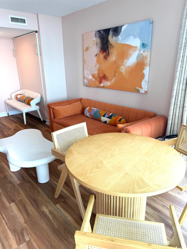 dining room featuring wood-type flooring and a textured ceiling