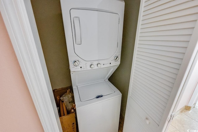 laundry room with light tile patterned flooring and stacked washer / drying machine