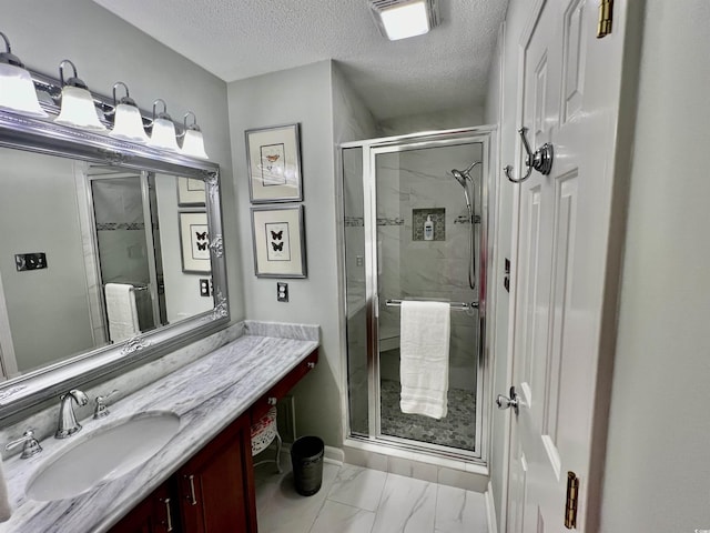 bathroom featuring a textured ceiling, marble finish floor, a shower stall, and vanity