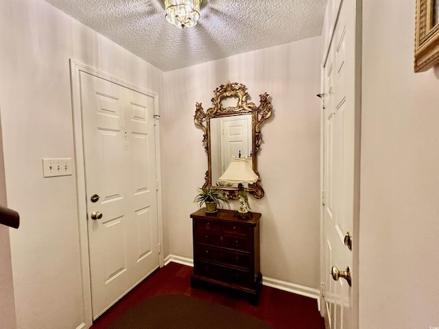 doorway to outside featuring a textured ceiling and baseboards