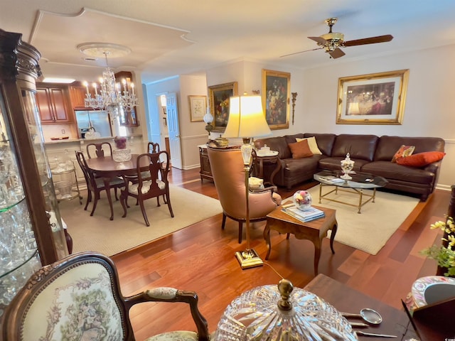 living room with ceiling fan with notable chandelier, hardwood / wood-style flooring, and crown molding